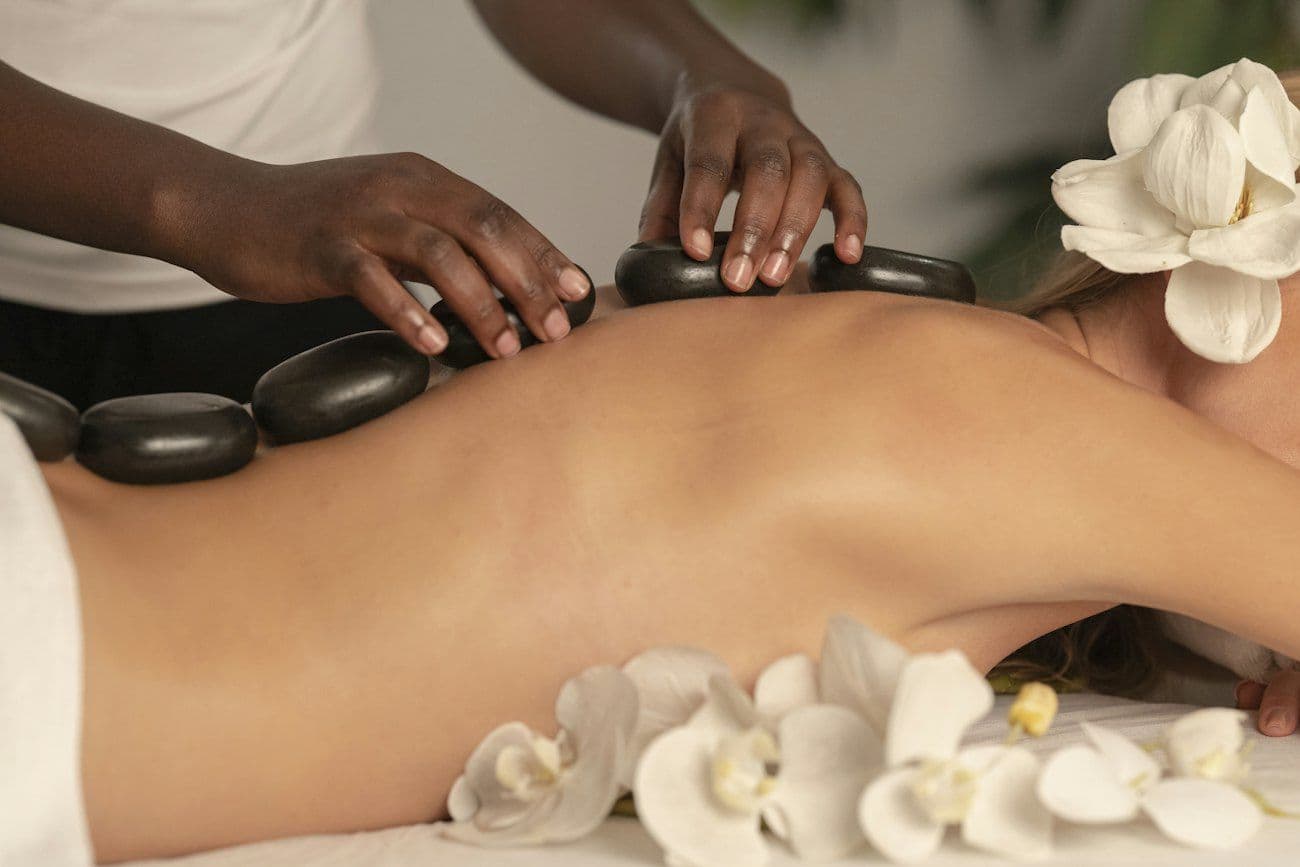 Hands placing warm stones on a client’s back